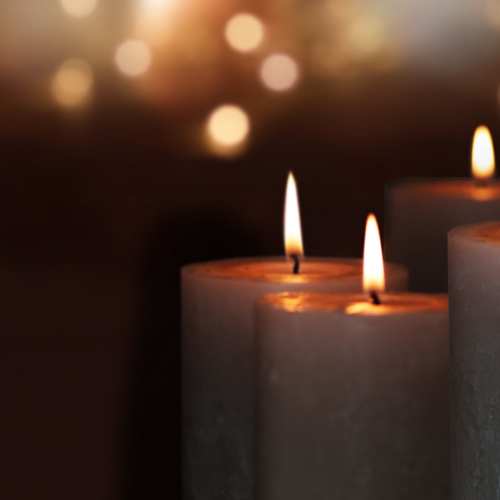 A trio of lit candles with a soft focus on the glowing flames, conveying a sense of warmth and serenity, reminiscent of the calming atmosphere Exposure Therapy Designs strives to provide in their therapeutic spaces.