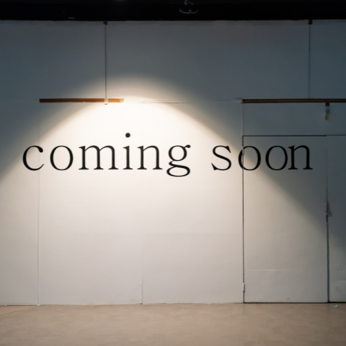 An anticipation-building image with the words 'coming soon' projected on a plain wall, illuminated by a single spotlight, symbolizing the new opportunities and developments to look forward to from Exposure Therapy Designs.